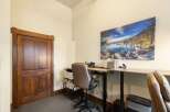 This office space features a beautiful wooden door and a large, scenic wall art that adds a touch of nature to the room.