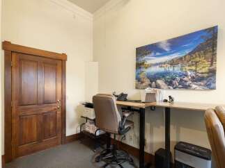 This office space features a beautiful wooden door and a large, scenic wall art that adds a touch of nature to the room.