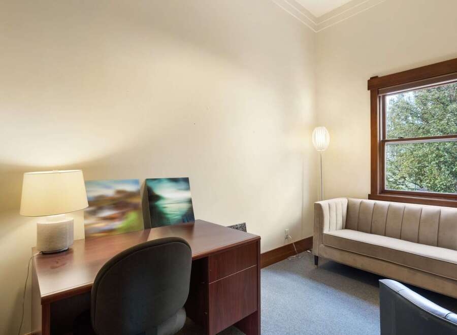 This inviting office space features a rich wooden desk with a classic lamp and two abstract art pieces, perfect for inspiring creativity.