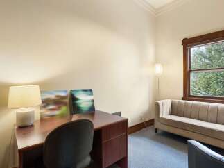 This inviting office space features a rich wooden desk with a classic lamp and two abstract art pieces, perfect for inspiring creativity.