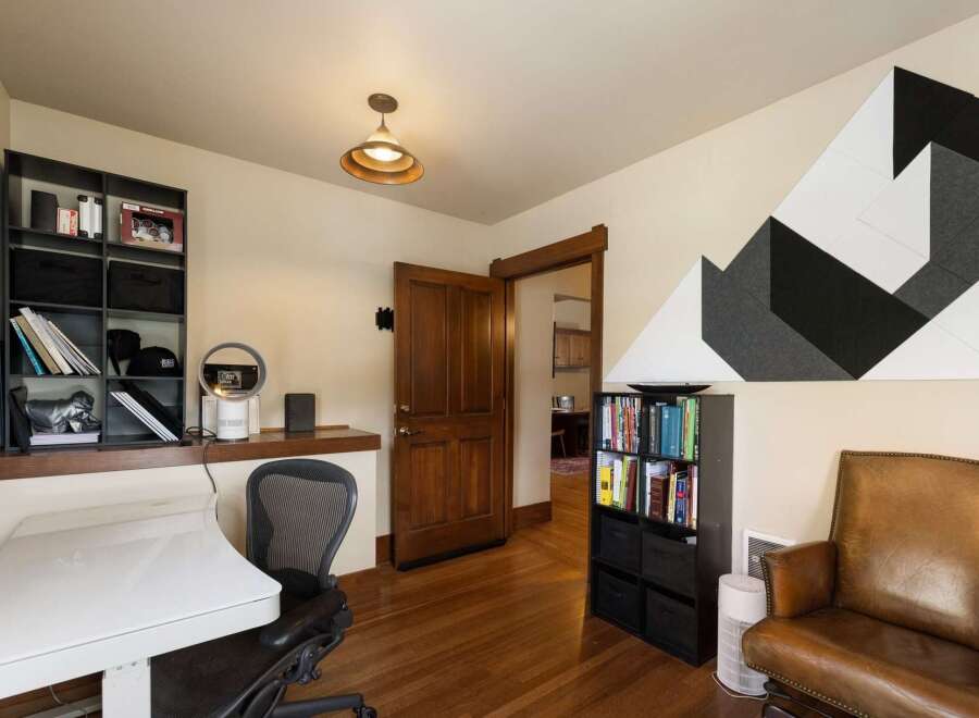 This home office features a modern white desk and a comfortable leather armchair, perfect for productive work sessions.