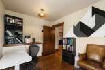 This home office features a modern white desk and a comfortable leather armchair, perfect for productive work sessions.