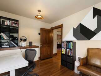 This home office features a modern white desk and a comfortable leather armchair, perfect for productive work sessions.