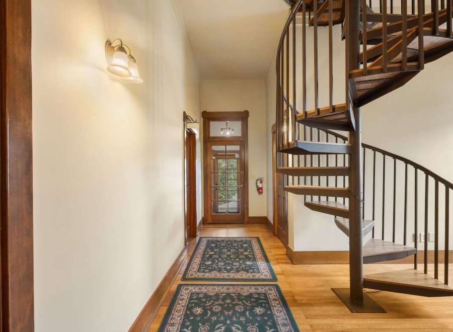 Step into this charming hallway featuring a stunning spiral staircase, perfect for adding a touch of elegance and maximizing space.