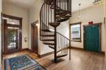 Discover unique charm in this inviting entryway featuring a striking spiral staircase as the centerpiece.