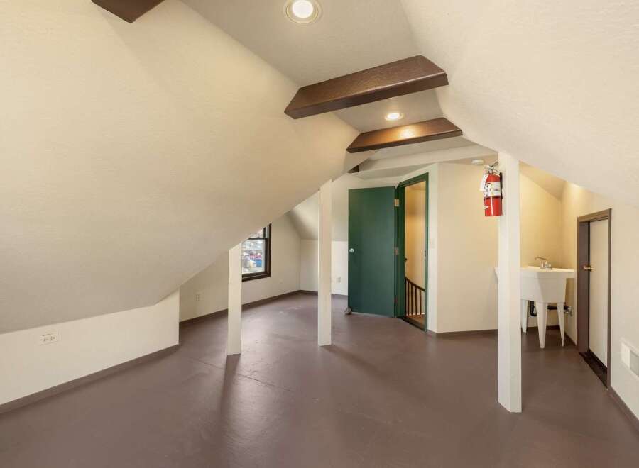 Discover the unique charm of this attic space, featuring exposed wooden beams and sloped ceilings that add character and warmth.