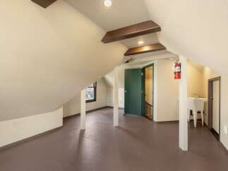 Discover the unique charm of this attic space, featuring exposed wooden beams and sloped ceilings that add character and warmth.