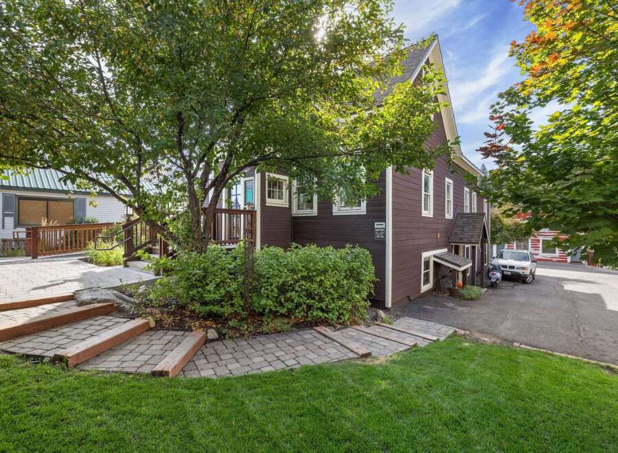 Discover this charming property featuring a welcoming exterior with a paved walkway leading to a wooden deck and lush green lawn.