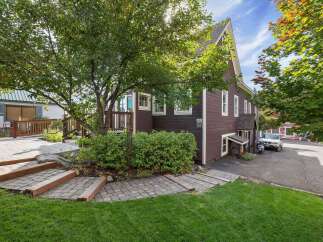 Discover this charming property featuring a welcoming exterior with a paved walkway leading to a wooden deck and lush green lawn.