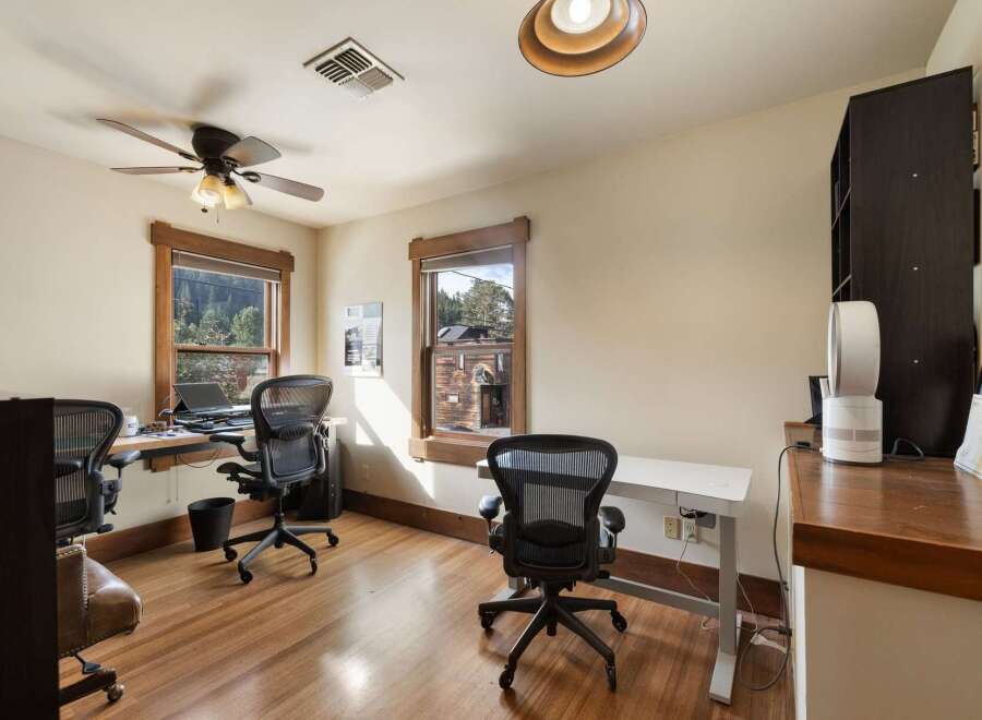 This home office features two workstations, each equipped with a comfortable ergonomic chair and a laptop.