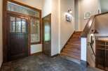 Step into a warm and inviting entryway featuring a rustic wooden door with glass panels, offering a glimpse of the natural beauty outside.