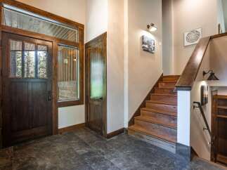 Step into a warm and inviting entryway featuring a rustic wooden door with glass panels, offering a glimpse of the natural beauty outside.