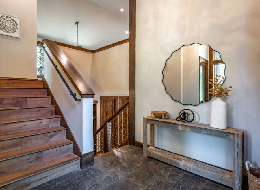 This stunning entryway features a beautiful wooden staircase with a sleek black railing, leading up to the main living areas.