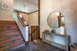 This stunning entryway features a beautiful wooden staircase with a sleek black railing, leading up to the main living areas.