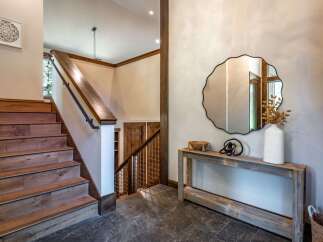 This stunning entryway features a beautiful wooden staircase with a sleek black railing, leading up to the main living areas.