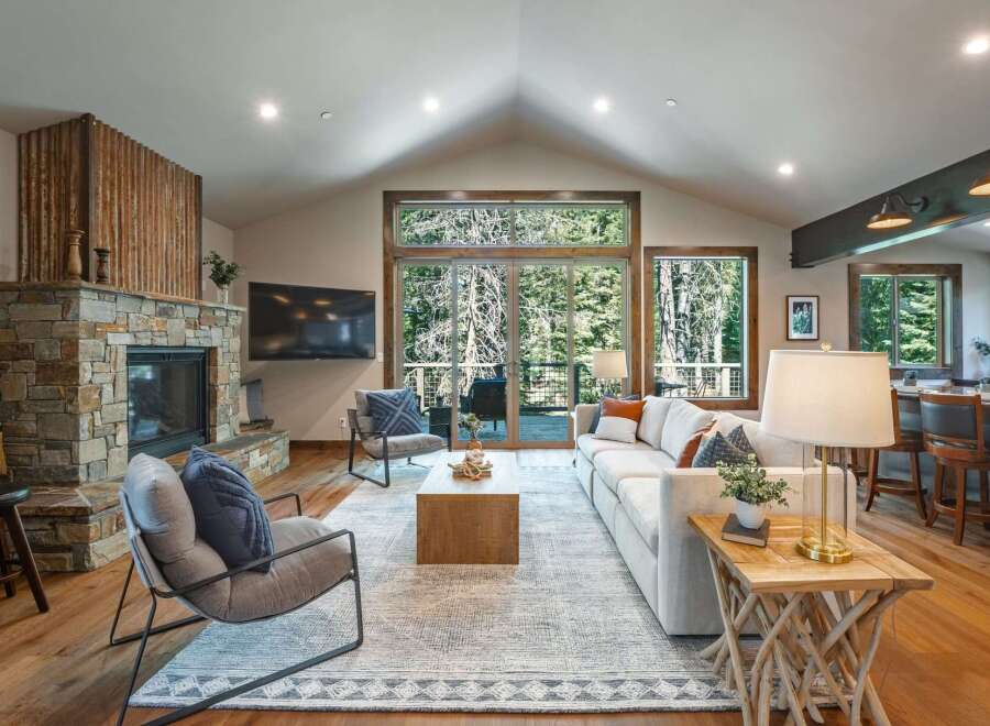 Experience luxurious mountain living in this stunning great room, featuring a grand stone fireplace and vaulted ceilings with exposed beams.