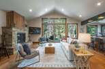 Experience luxurious mountain living in this stunning great room, featuring a grand stone fireplace and vaulted ceilings with exposed beams.