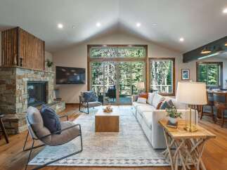Experience luxurious mountain living in this stunning great room, featuring a grand stone fireplace and vaulted ceilings with exposed beams.