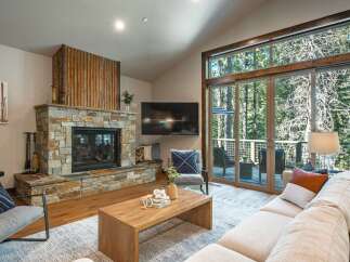 Experience modern mountain living in this stunning living room, featuring a striking stone fireplace and expansive windows that bring the outdoors in.