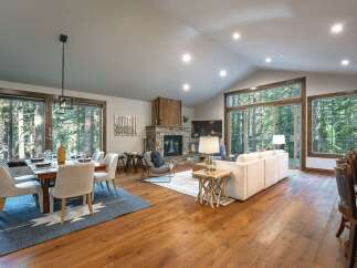 Experience luxurious mountain living in this stunning open-concept great room, featuring a cozy stone fireplace and expansive windows that flood the space with natural light.