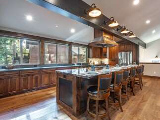 Experience luxury mountain living in this stunning kitchen, featuring rich wood cabinetry and a spacious granite island perfect for entertaining.