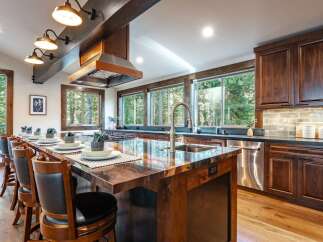 Experience luxury mountain living in this stunning kitchen, featuring a large island with a granite countertop and bar seating, perfect for entertaining.