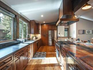 Experience rustic elegance in this stunning kitchen, featuring rich cherry wood cabinetry and a dramatic, multi-colored granite countertop.