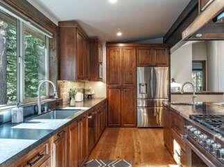 Experience luxury in this stunning kitchen featuring rich, dark wood cabinetry and sleek, modern stainless steel appliances.