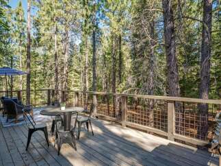 Enjoy the serene mountain lifestyle on this spacious deck, perfect for outdoor dining and relaxation amidst towering pine trees.