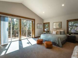 Experience serene living in this stunning bedroom featuring a vaulted ceiling and abundant natural light streaming through large sliding glass doors.