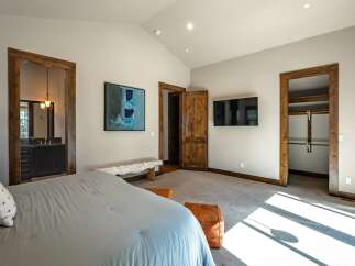 Experience luxury in this spacious master bedroom, featuring a vaulted ceiling and a modern flat-screen TV.