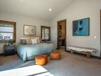 Experience rustic luxury in this master bedroom, featuring a plush king-sized bed adorned with soft, neutral linens and accent pillows.