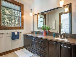 Experience rustic elegance in this beautifully appointed bathroom, featuring a spacious double vanity with dark wood cabinetry and a sleek quartz countertop.