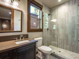 This modern bathroom features a sleek vanity with a stone countertop and dark wood cabinetry, complemented by a large ornate mirror.