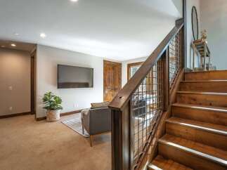 Experience modern rustic charm in this inviting living space, featuring a sleek flat-screen TV mounted on a neutral wall and a comfortable grey sofa perfect for relaxation.
