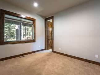 This room features a large wooden-framed window offering serene forest views, complemented by plush carpeting and rich wood trim.