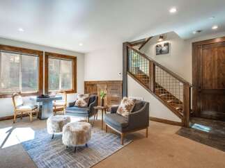 Step into this inviting living space featuring comfortable seating, including plush armchairs and cozy fur ottomans, perfect for relaxation.