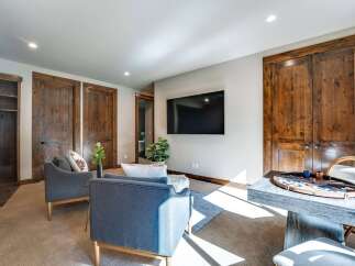 Experience rustic charm and modern comfort in this inviting living space, featuring a large flat-screen TV mounted on a neutral wall and bathed in natural light.