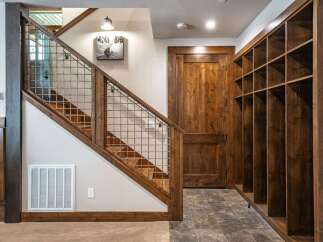 This charming entryway features a rustic wooden staircase with a unique metal grid railing, leading to the upper level.
