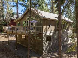 Nestled amongst tall pine trees, this charming home offers a serene retreat with a spacious wooden deck perfect for outdoor living.