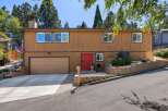 Discover this charming home featuring a warm wood exterior and a striking red front door, creating an inviting entryway.