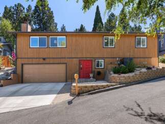 Discover this charming home featuring a warm wood exterior and a striking red front door, creating an inviting entryway.