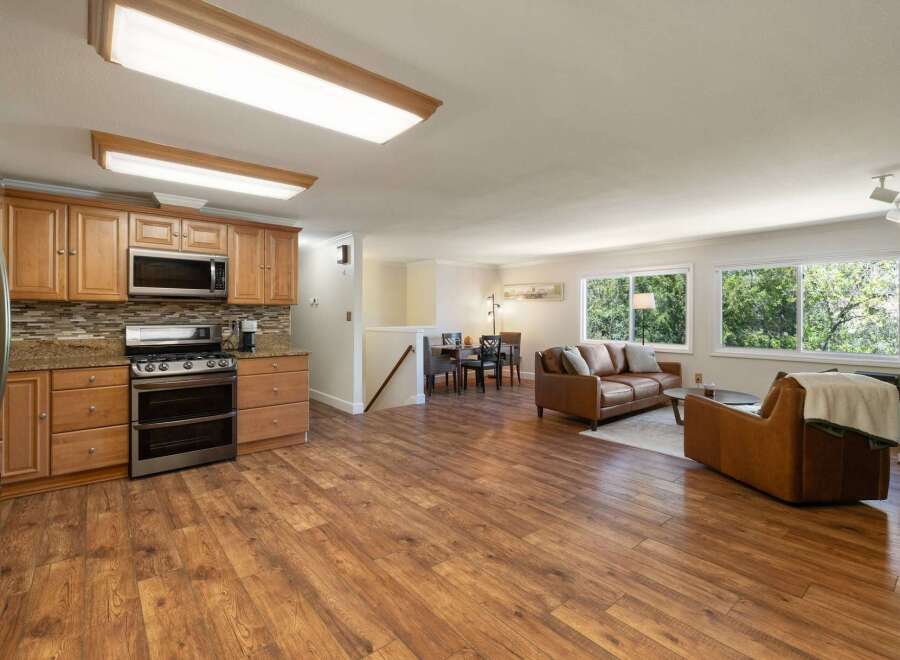 Discover this charming open-concept living space, featuring a modern kitchen with ample cabinetry and granite countertops, seamlessly flowing into a cozy living area.