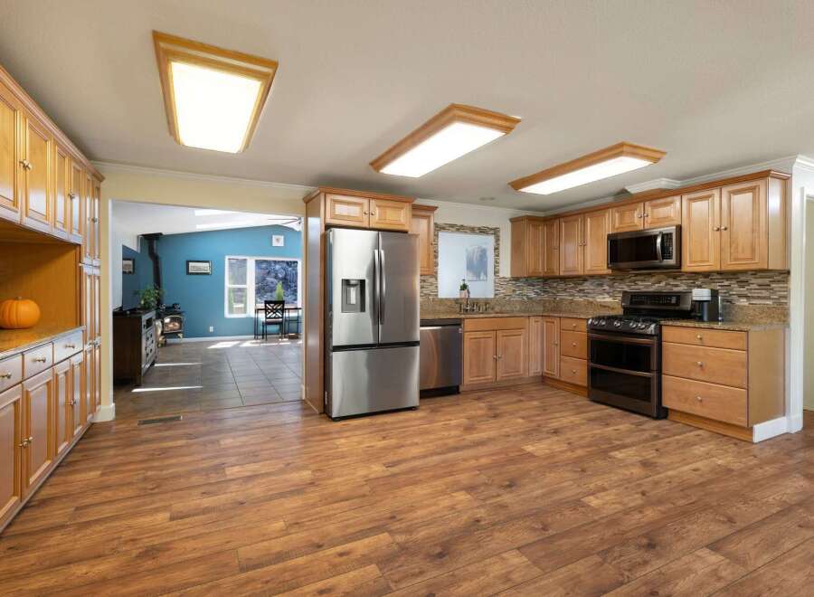Discover this spacious kitchen featuring warm wood cabinetry, granite countertops, and a sleek stainless steel refrigerator.