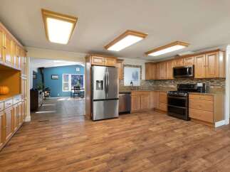 Discover this spacious kitchen featuring warm wood cabinetry, granite countertops, and a sleek stainless steel refrigerator.