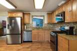 This spacious kitchen features beautiful light wood cabinetry, granite countertops, and a stylish mosaic tile backsplash.
