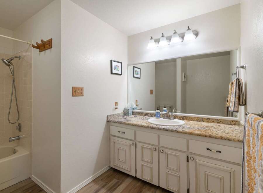 This charming bathroom features a bathtub/shower combo with tiled walls and a chrome showerhead.