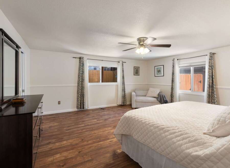 This spacious bedroom features a large dresser with a mirror, a comfortable seating area, and a ceiling fan for added comfort.