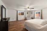This spacious bedroom features a large dresser with a mirror, a comfortable seating area, and a ceiling fan for added comfort.