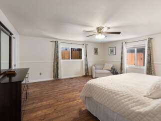 This spacious bedroom features a large dresser with a mirror, a comfortable seating area, and a ceiling fan for added comfort.
